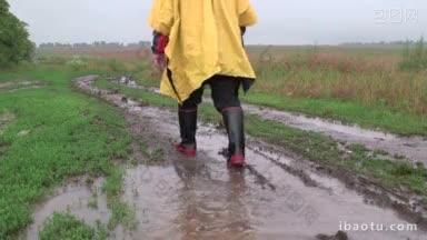 一个穿着黄色雨衣的人<strong>在</strong>雨中穿过田野，走<strong>在</strong>一条土<strong>路上</strong>